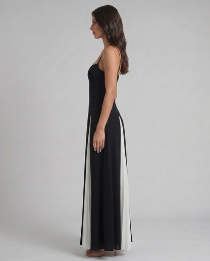 Side profile of white and black maxi dress showing slim silhouette, thin straps, and pleated skirt detail