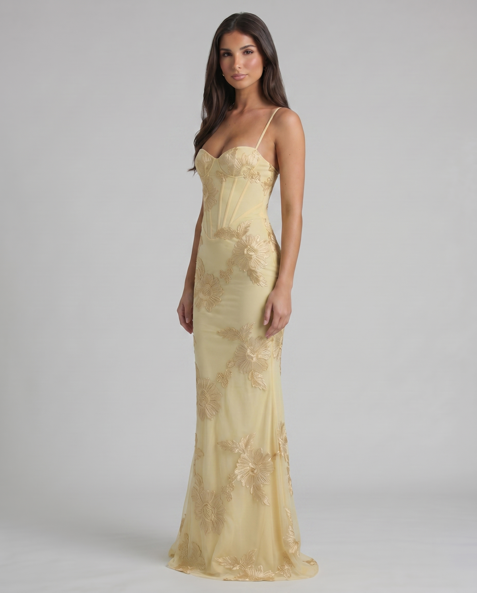 Angled front view of yellow maxi dress highlighting fitted waist, corset seams, and embroidery