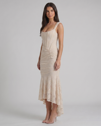 Angled view of beige lace corset maxi dress with wide straps, ruched hip detail and flared hem