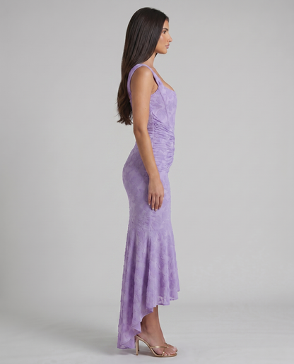 Side profile of lavender corset maxi dress with ruched midsection and cascading high-low ruffle hem
