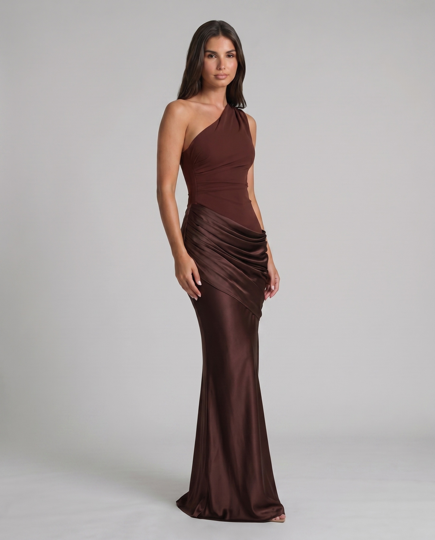 Angled view of brown one-shoulder maxi dress, smooth bodice and ruched drape skirt