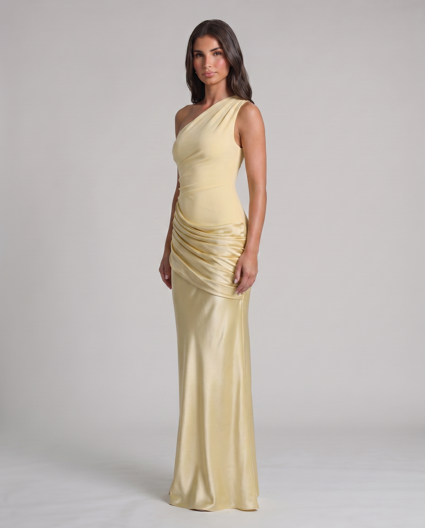 Three-quarter view of yellow one-shoulder maxi dress with satin ruched wrap detail at hips