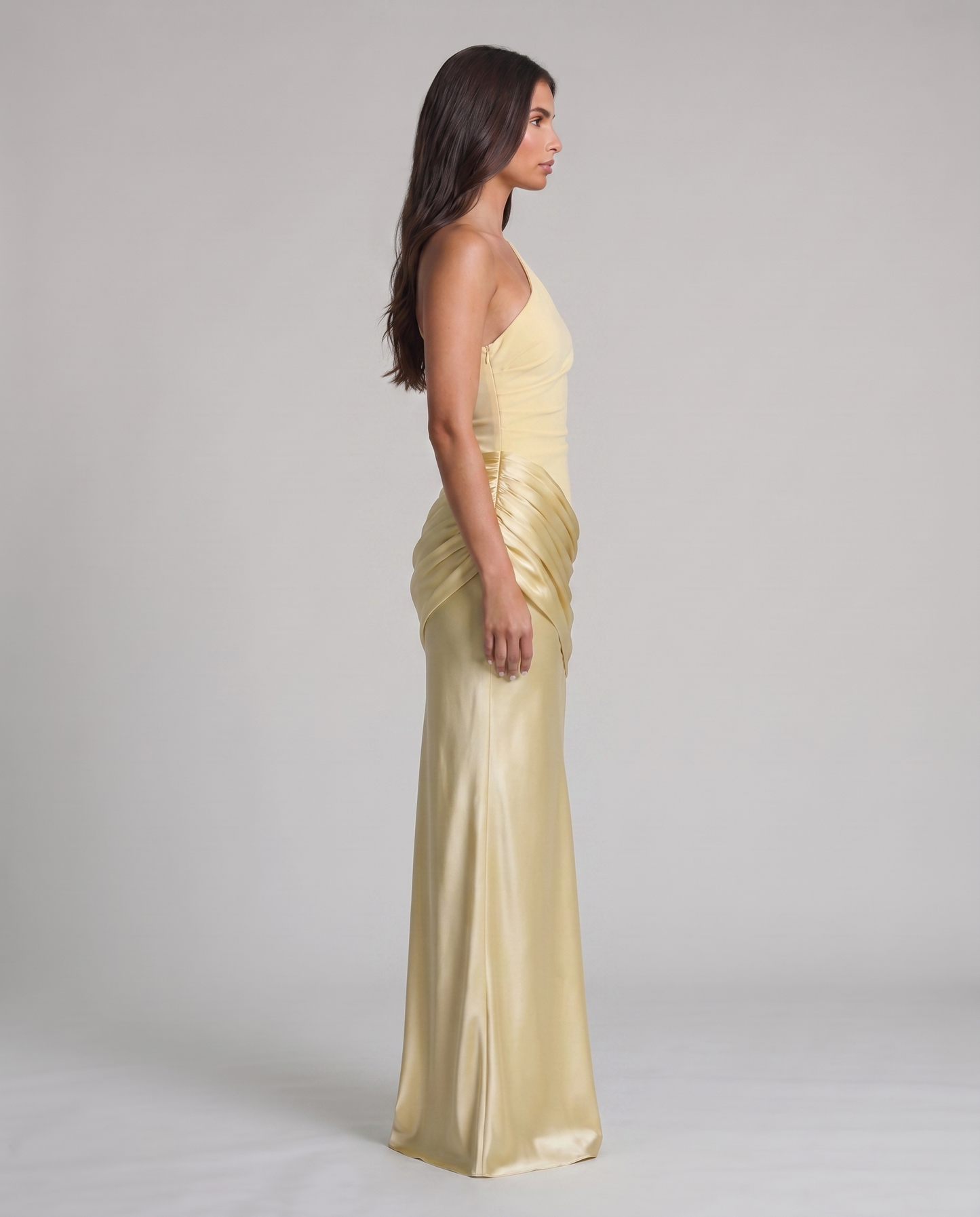 Side profile of yellow one-shoulder maxi dress with fitted bodice, gathered hip overlay, long skirt