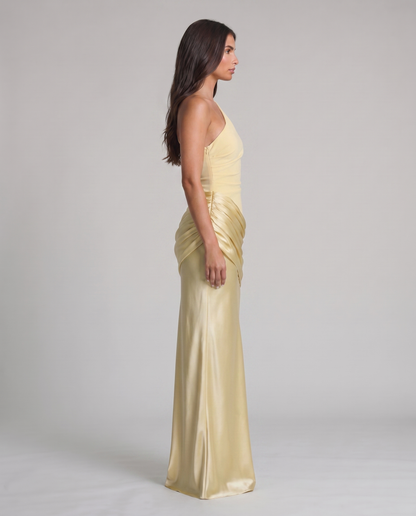 Side profile of yellow one-shoulder maxi dress with fitted bodice, gathered hip overlay, long skirt