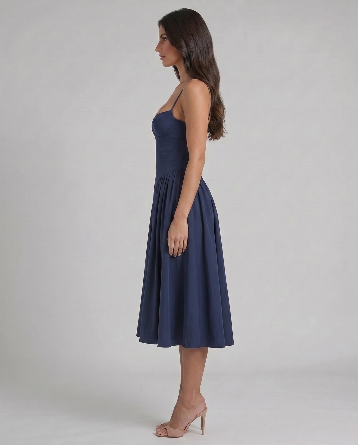 Left side view of blue midi dress highlighting slim straps, contoured bodice and softly pleated skirt