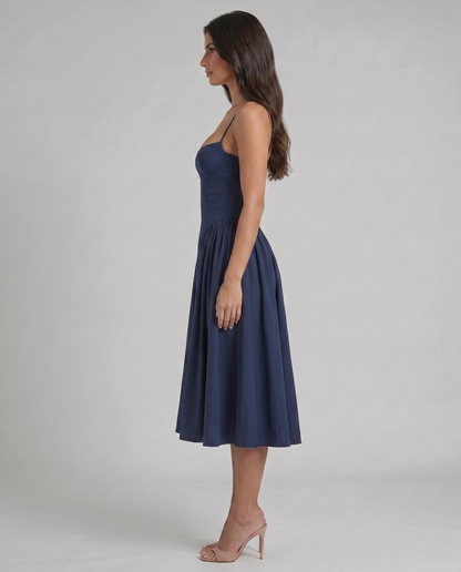 Left side view of blue midi dress highlighting slim straps, contoured bodice and softly pleated skirt