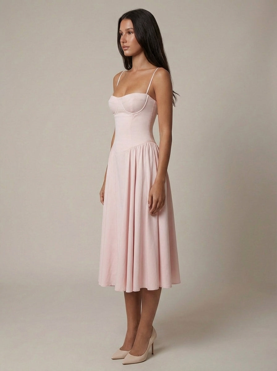 Side view of blush pink midi dress showing slim straps, corset-style bodice, and soft pleated skirt