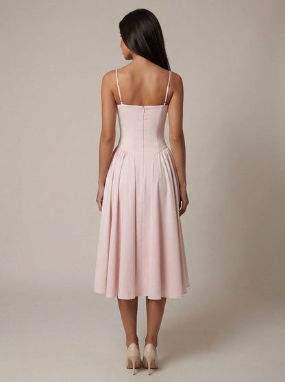 Back view of blush pink midi dress with adjustable spaghetti straps, fitted bodice, and midi-length flare