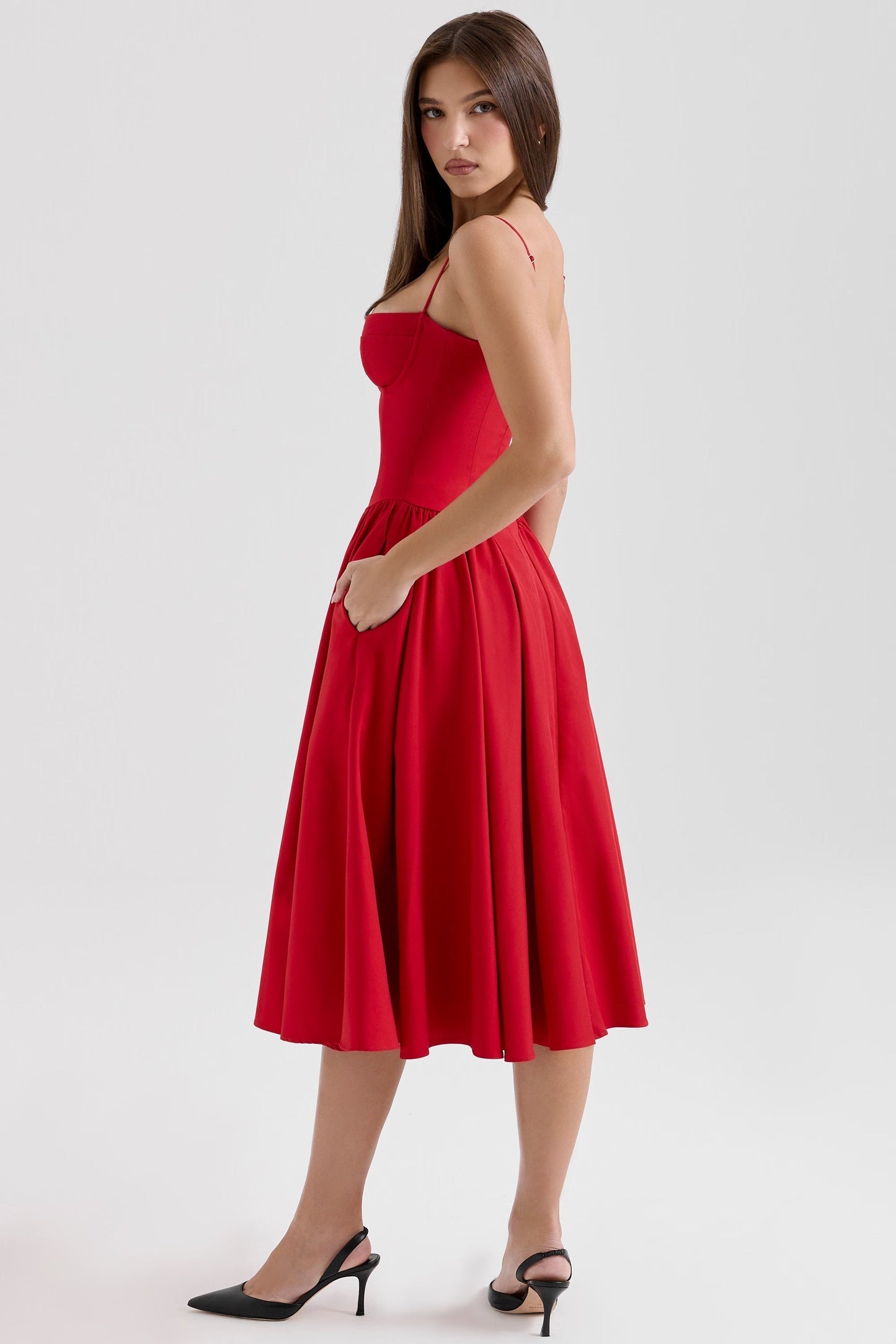 Profile shot of red midi dress with fitted bodice and flowing skirt, side silhouette on white