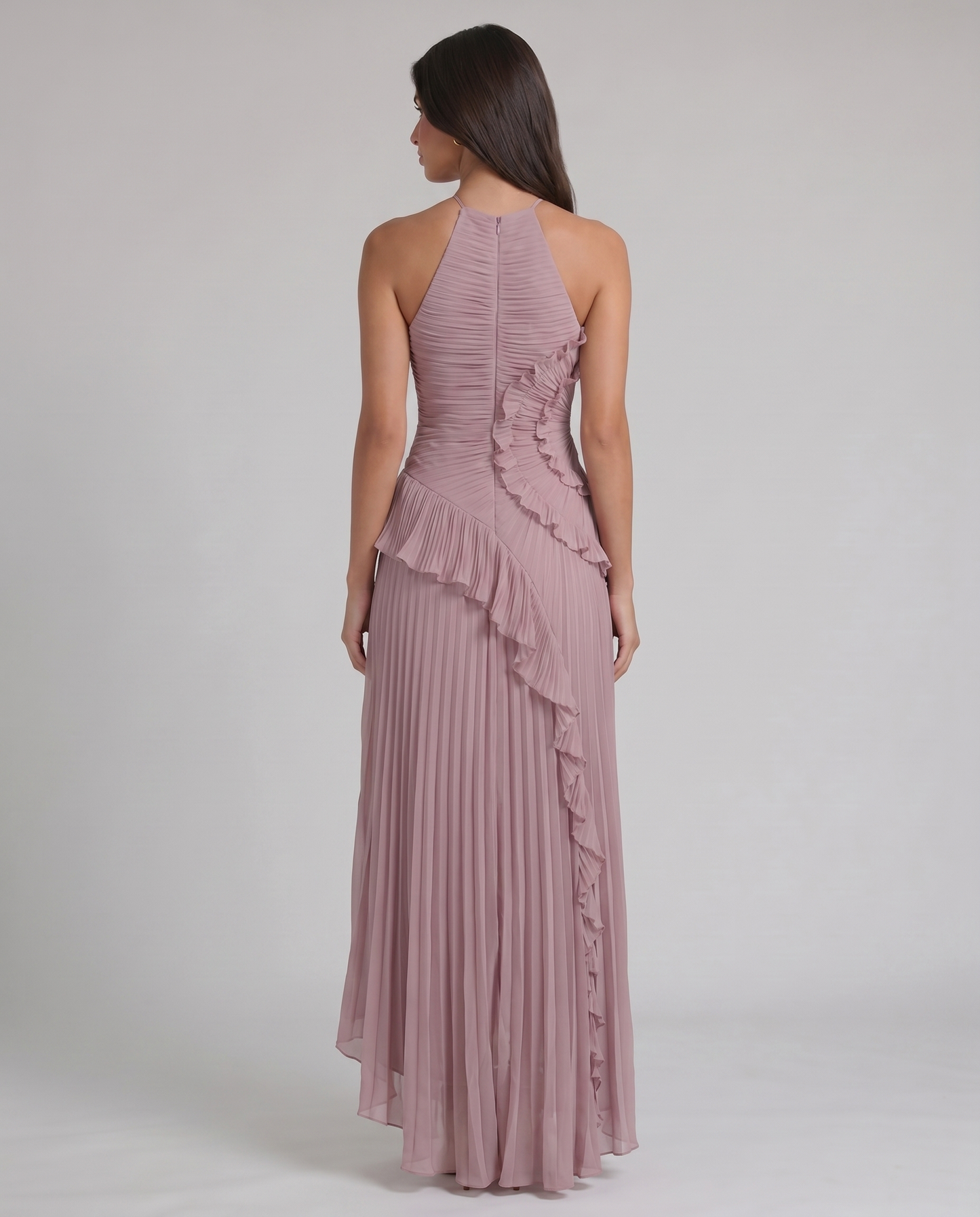 Back view of pink halter-neck maxi dress showing center zipper, pleated skirt, and ruffle accent at waist