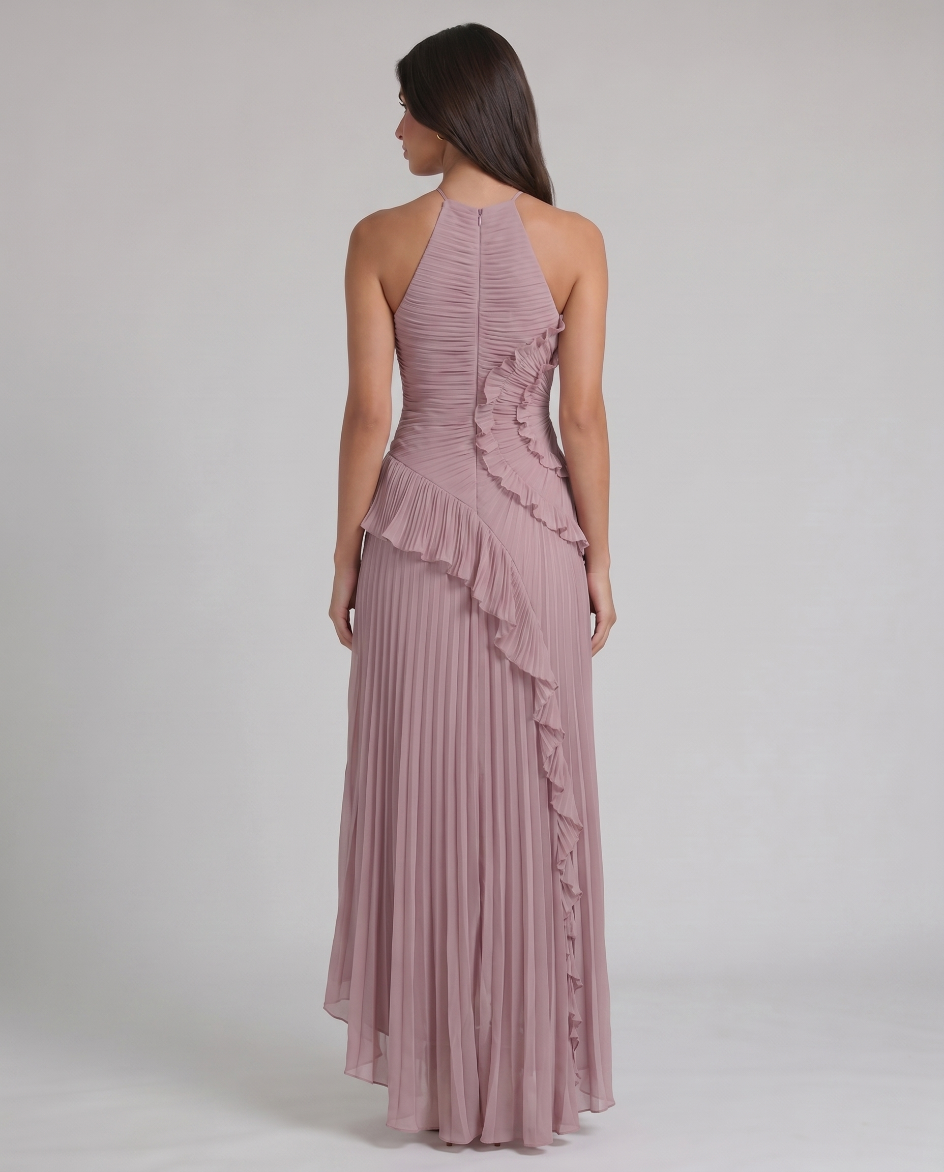 Back view of pink halter-neck maxi dress showing center zipper, pleated skirt, and ruffle accent at waist
