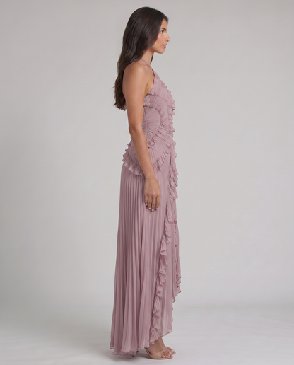 Side profile of pink pleated maxi dress with fitted ruched bodice, layered ruffles, and flowy skirt