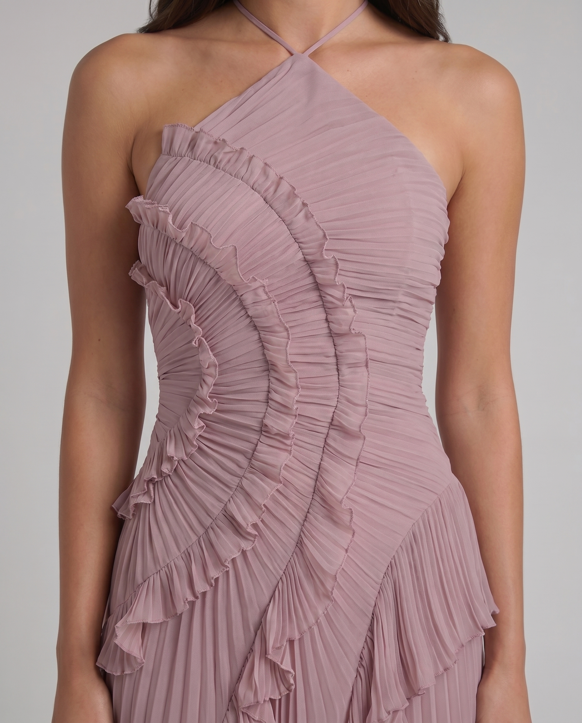 Close-up of pink halter maxi dress bodice with fine pleats, ruched texture, and stitched ruffle trim