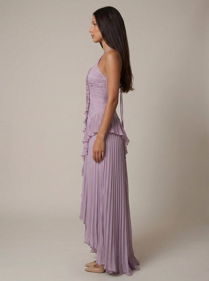 Full side view of purple halter maxi dress highlighting pleated skirt drape and asymmetrical hem