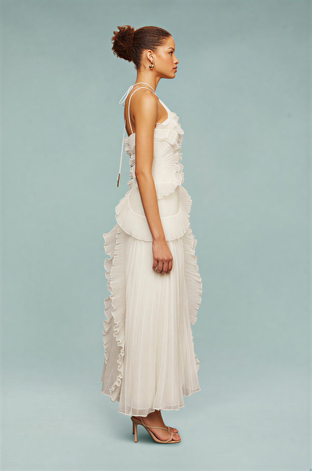 Left side view of white maxi dress showing ruffle edge trim down the skirt and sheer pleated fabric