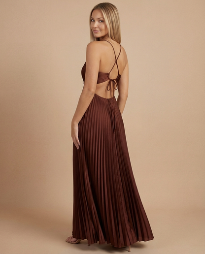 Three-quarter back angle of brown pleated maxi dress featuring open back tie and flowing pleated skirt