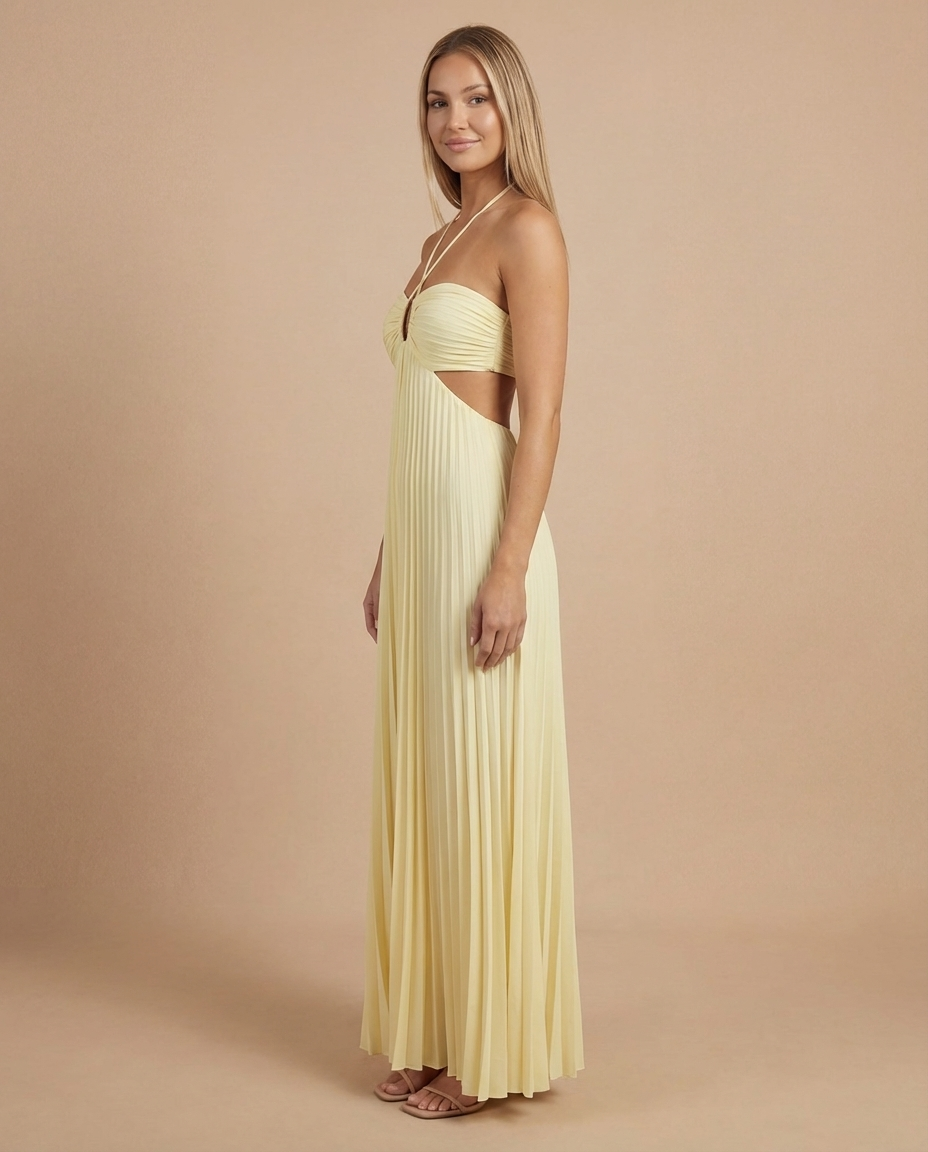 Side view of yellow pleated maxi dress showing waist cutout, halter neckline and flowing skirt