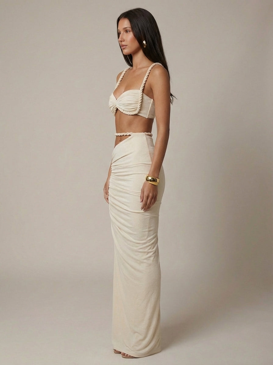 Side profile of cream two-piece maxi skirt set featuring twisted rope straps and ruched skirt